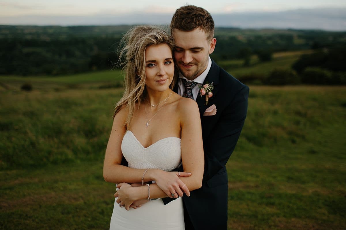 Engaged couple embracing in a field at golden hour