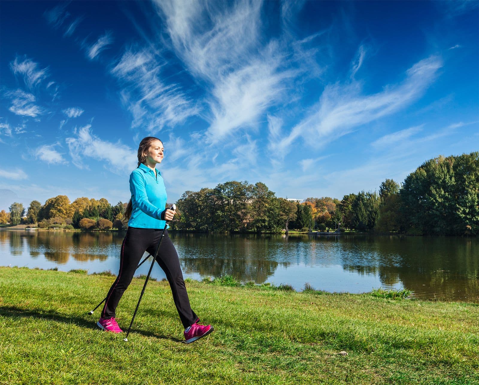 Woman walking beside a lake on a bright fall day